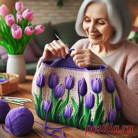 Здесь может быть: пожилая женщина, вяжущая с фиолетовыми цветами, связанными крючком, на сумке и клубками пряжи рядом с ней.