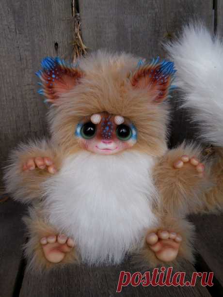 This may contain: a small stuffed animal with blue eyes and white fur on it's legs, sitting on a wooden surface