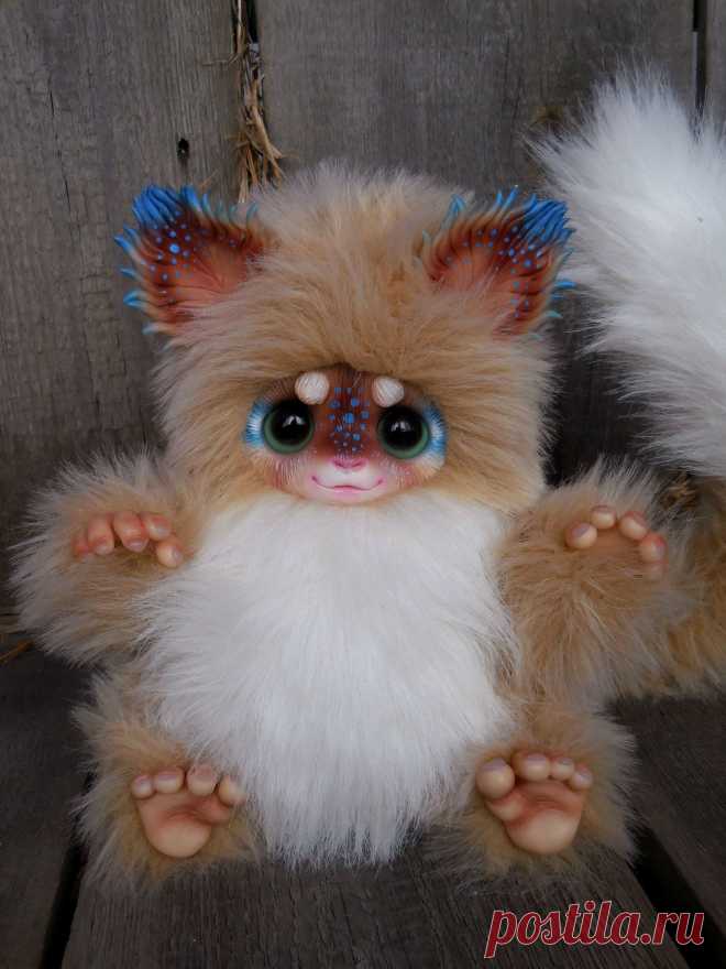 This may contain: a small stuffed animal with blue eyes and white fur on it's legs, sitting on a wooden surface