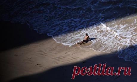 Бразилец загорает в одиночестве между тенями двух зданий — Фото дня, 24 июня 2013