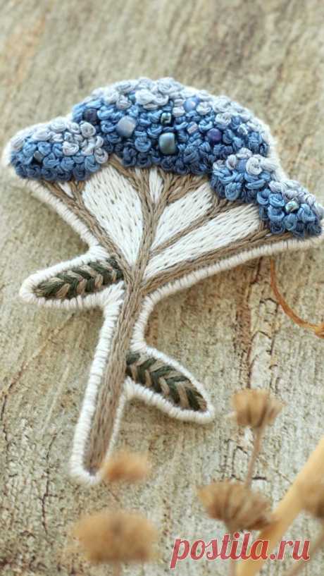 a close up of a flower on a piece of wood with blue and white beads