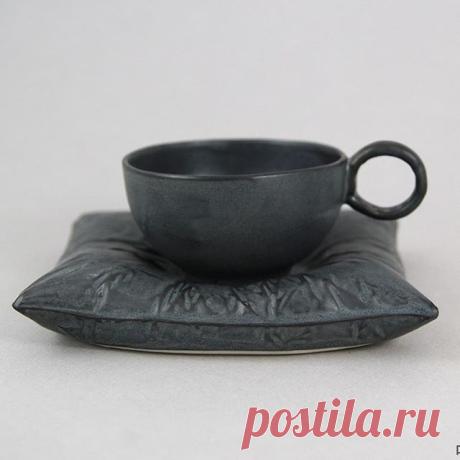 ЧАШКА НА ПОДУШКЕ.
ПОЛЬСКАЯ КЕРАМИКА. 
Чашка на подставке в виде подушки. Изготовлена вручную из фарфоровой массы и покрыта глазурью в цвете "графит". Обожжена при температуре 1250 С. Подходит для мытья в посудомоечных машинах. 
Емкость чашки 150 мл (выс. 5см / диам. 8,5 см)
Подушка ( 15 x 13 x 3 см ) 
Мастерская PANJEZIORKO - керамические fikumiku, то есть продукты воображения, запечатленные в высоких температурах. Иногда мягкие и забавные, иногда строгие в своей простот...