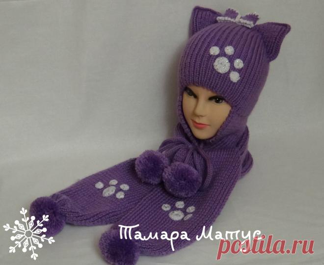 Забавная и игривая шапка-кошка с помпонами для девочки выполнена спицами без швов из полушерстяной пряжи.
Шапочка  очень теплая,толстенькая, плотной вязки рассчитана на межсезонье и зиму. К шапке в комплект связан спицами шарф с помпонами.
