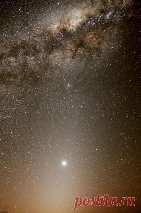 На этом блестящем небесном пейзаже выпуклый центр нашей галактики Млечный Путь отдыхает на подушке из света. На фотографии, сделанной 22 сентября на фоне тёмных небес Южной Африки, пылевые потоки будто бы стекают вниз из Галактического центра к желтоватому Антаресу — ярчайшей звезде созвездия Скорпиона, расположенной в верхней части композиции. Однако, самая яркая небесная жемчужина на снимке совсем не звезда, а планета Венера, сияние которой всё ещё господствует над западным горизонтом.