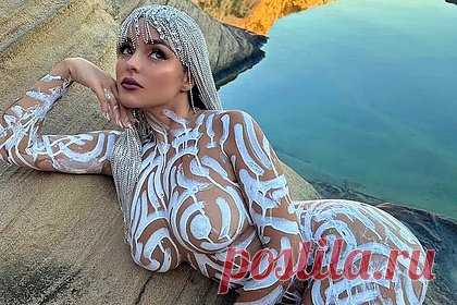 Модель OnlyFans снялась голой с краской на теле. Британская манекенщица Деми Роуз поделилась снимками в откровенном образе. 28-летняя модель OnlyFans позировала голой, лежа на камне рядом с горным озером. При этом обнаженные части тела знаменитости прикрывал узор, нарисованный на ее коже краской белого цвета. Среди прочего она надела состоящий из стразов парик.