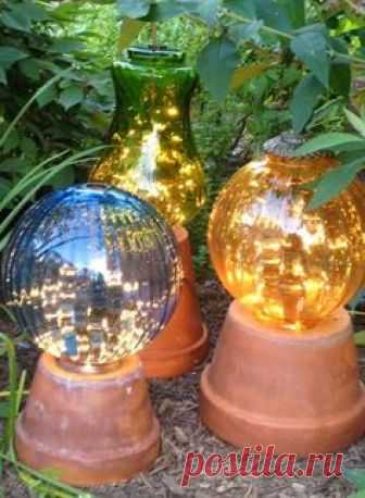 DIY - Garden lights made from flower pots and old lamp globes with strings of white lights in the globes.