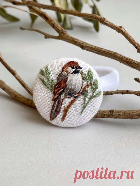 a small bird sitting on top of a tree branch next to a white cloth ring