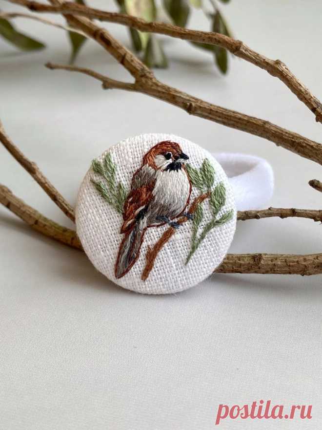 a small bird sitting on top of a tree branch next to a white cloth ring