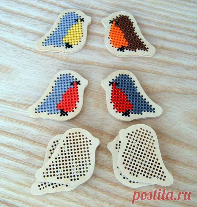 four pieces of cross - stitched birds sitting on top of a wooden table