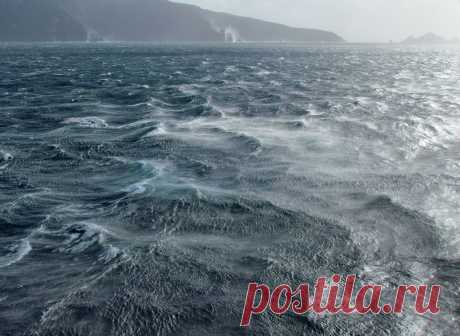 Things were getting a bit choppy out there This view, looking east from our sheltered position near Cape Horn Navy Station, shows a choppy sea between the ship and Deceit Island, which is the land we see in the distance in this picture. I enjoyed watching the strong westerly winds pick up a mist from the blue-green ocean surface spreading it eastwards.  The small jagged islands on the right are part of the so-called Los dientes de Deceit (or Teeth of Deceit).