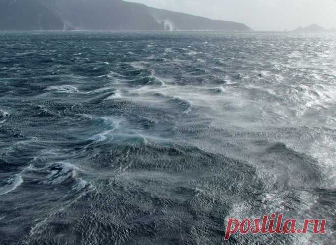 Things were getting a bit choppy out there This view, looking east from our sheltered position near Cape Horn Navy Station, shows a choppy sea between the ship and Deceit Island, which is the land we see in the distance in this picture. I enjoyed watching the strong westerly winds pick up a mist from the blue-green ocean surface spreading it eastwards.  The small jagged islands on the right are part of the so-called Los dientes de Deceit (or Teeth of Deceit).