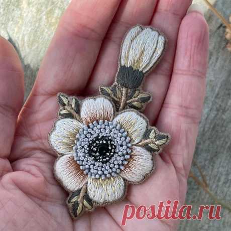a hand holding a flower brooch in it's palm