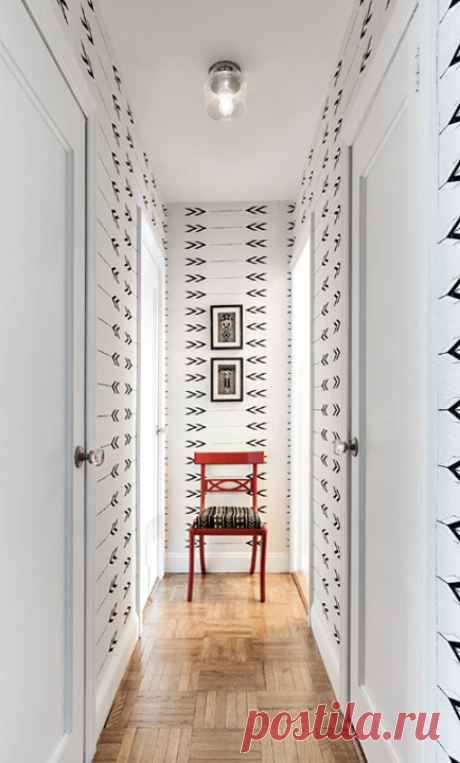 Лайфхак для прихожей: Если узкая прихожая-коридор заканчивается простенком, поместите на него источник света и броский элемент, например, картину. Светильник сыграет роль визуального маячка, а картина, особенно крупная, приблизит стену — коридор будет казаться менее вытянутым. В примере на фото орнамент обоев «направляет взгляд», а красный стул — служит фокусной точкой. Источник: