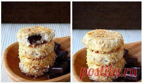 Вкусные сырники к завтраку. = Ингредиенты: 
600 г творога
1 яйцо
0,5 стакана манки
0,5 стакана сахара (или по вкусу)
ванилин
100 г шоколада
овсяные хлопья для панировки

Приготовление:

Смешать творог, яйцо, манку, сахар и ванилин и вымесить тесто.
Шоколадку поломать на кусочки.

Из теста формировать лепешку, класть кусочек шоколада, защипывать и формировать сырники.

Обвалять сырники в овсяных хлопьях и обжарить до готовности.