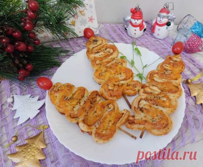 Закусочные елочки с беконом и сыром. Закусочные елочки с беконом и сыромСлоеное тесто заранее разморозить. Раскатать.Выложить первым слоем полоски бекона. На бекон выложить пластины сыра.Тесто сложить вдвое, начинкой внутрь. Разрезать на 4 полоски, затем каждую полоску еще пополам. Елочку будем собрать на шпажок: присборить и нанизать на шпажок по 2 полоски в виде елочки (см. фото).Выпекать в разогретой до 180 градусов в духовке в течение 25- 30 минут.Перед подачей украсить верхушку елочки…