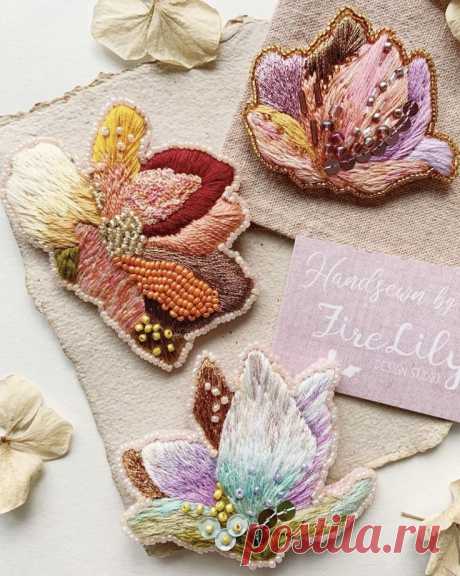 three embroidered flowers are sitting on a piece of fabric