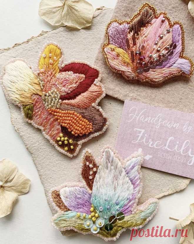 three embroidered flowers are sitting on a piece of fabric
