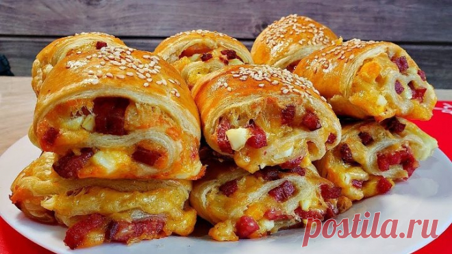 Делаю такие целый МЕСЯЦ каждые выходные и всегда мало. Перекус выходного дня трудно отказаться, он такой вкусный что готовить нужно побольше. хорошо подходит под просмотр фильма или футбола.
   ♦ слоеное дрожжевое тесто 500 гр
   ♦ твердый сыр 200 гр
   ♦ колбаса любая по вашему вкусу 200-300 гр
   ♦ 2 шт куриное яйцо отваренные
   ♦ 1 шт куриное яйцо сырое 
   ♦ майонез 3 ст,л 
   ♦ кунжутные семечки 
 Приятного аппетита !!!