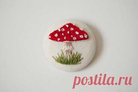 a red and white mushroom brooch sitting on top of a white surface