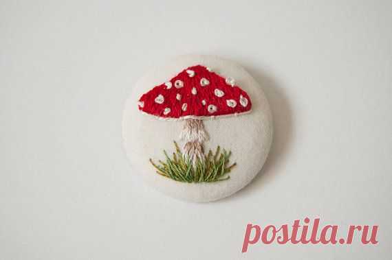 a red and white mushroom brooch sitting on top of a white surface