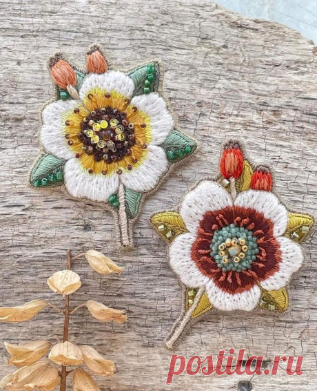 three embroidered flowers sitting on top of a piece of wood