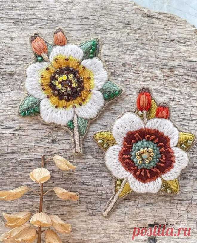 three embroidered flowers sitting on top of a piece of wood