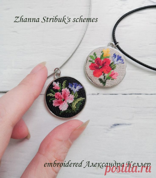 a hand is holding two pendants with flowers on them
