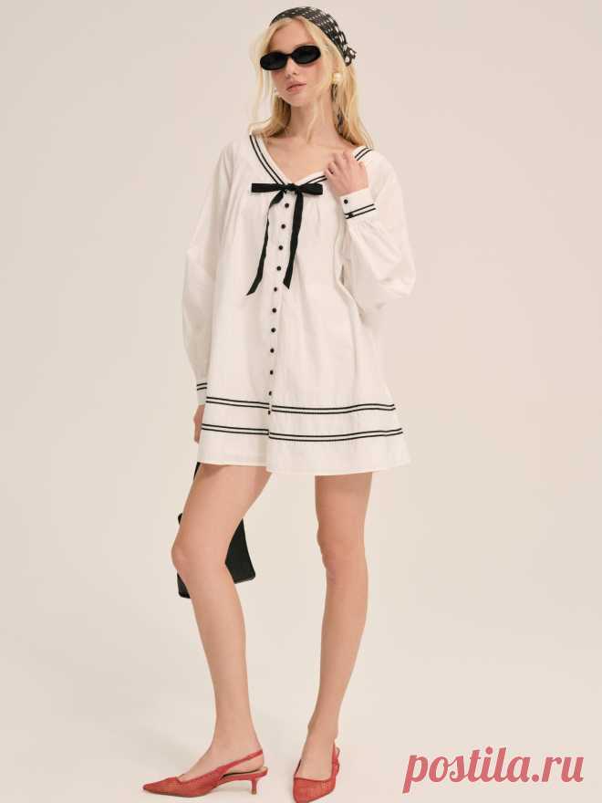 Shelly Mini Dress — White Inspired by nostalgic ’50’s silhouettes, the Shelly babydoll mini dress exudes vintage charm. This cotton long sleeve mini dress features charming contrast striped piping throughout, center-front buttons, a gathered bodice and sleeves, and a contrast decorative bow at neckline.
