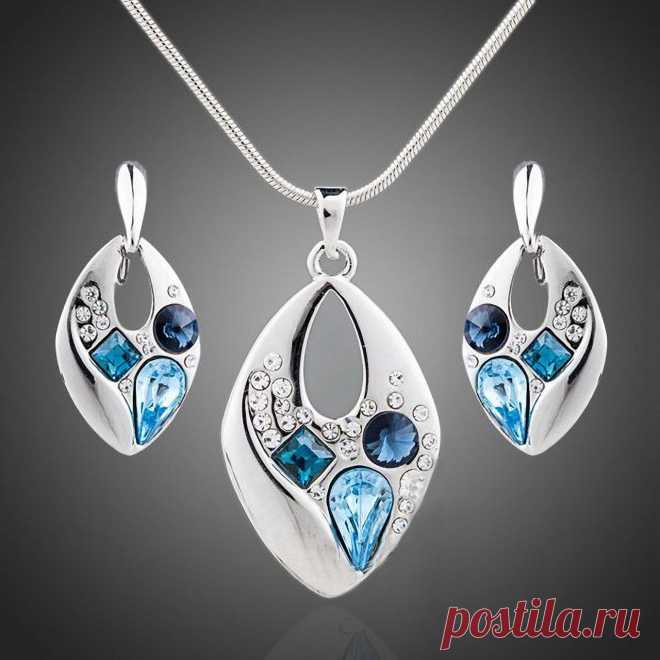 В идеальную каплевидную форму этих украшений, ассиметрично, и в то же время органично вписались кристаллы голубого, синего и нейтрального цвета. Такое сочетание правильных форм и блестящих, хаотично расположенных искрящихся камней, понравится любой моднице. Этот комплект обязательно привлечет внимание к его обладательнице, выгодно подчеркнет грациозную женскую шею и зону декольте. Будет гармонировать с цветом глаз и соответствующим макияжем, послужит дополнением к красивой модельной прическе