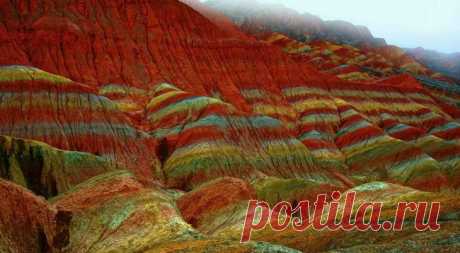 Ландшафт Дэнксия — цветные горы Китая Яркие краски радуют глаз — красноватый песчаник местных гор играет на солнце множеством оттенков. Цветные горы Китая испещрены рисунками причудливой формы, напоминающими морские волны.Сегодня туристы ...