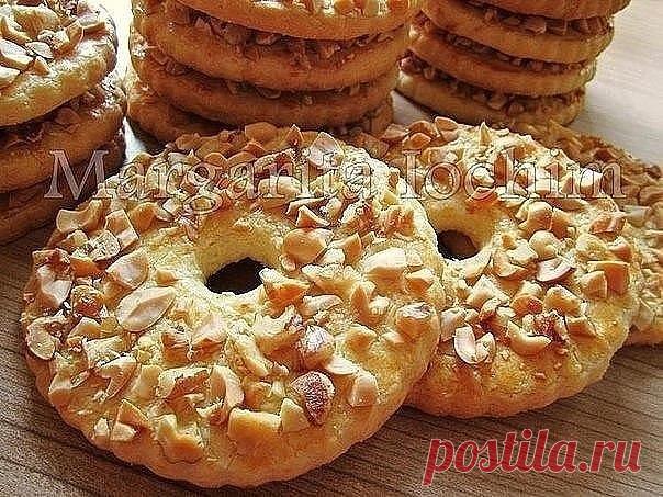 Песочные кольца с орехами.
 
Тесто:
250 г сливоч. масла (холодного) - порезать кусочками
150 г сахара
1 яйцo (среднее)
1 п. ванил. сахара (8 г)
1 ч. л. с горкой разрыхлителя (5 г)
2,5 ст. муки (400 г) - просеять
 
Дополнительно:
1 ст. жареного арахиса (160 г) - порубить не мелко ножом
 
Для смазывания:
1 желток + 2 ст. л. молока - перемешать вилочкой
 
В чашку выкладываем масло, сахар, яйцо, ванил. сахар и разрыхлитель - слегка перемешиваем.
Постепенно подсыпая муку, замеш...