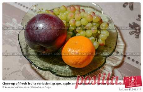 Close-up of fresh fruits variation, grape, apple and tangerine in green glass plate on table Стоковое фото, фотограф Анастасия Усанина / Фотобанк Лори