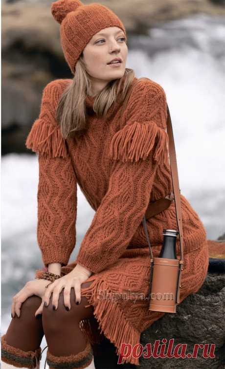 Оранжевый комплект – шерстяной пуловер и юбка связаны узором из кос и украшены длинной бахромой, дополняет образ шапка с помпоном.