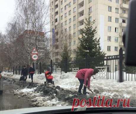 Молодая мама с лопатой расчищает тротуар чтобы была возможность проехать с коляской. Уфа, 2017 год