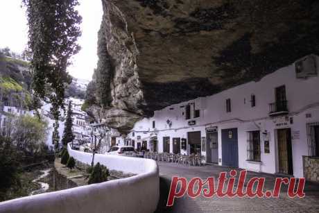ОГРОМНЫЕ СКАЛЫ, НАВИСАЮЩИЕ НАД УЛИЦАМИ Базальтовые скалы на улицах "Сетениль-де-лас-Бодегас". Испания ⠀ Лежащий в горах Андалусии Сетениль-де-лас-Бодегас являет собой удивительный архитектурный ландшафт: многотонные скальные своды, нависающие над улицами и переулками городка, защищают его от пронизывающих ветров и палящего зноя. Дома, будто бы врезанные в базальтовые скалы, являются продолжением природных каменных пещер.