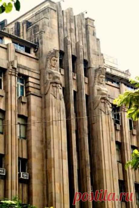 Art Deco building in Mumbai, India with two elongated statues flanking the door. They are armed and dangerous.
