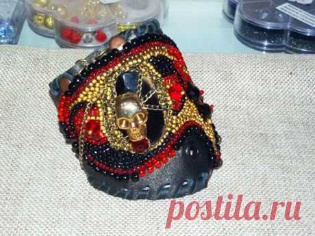 А вот это уже немного интереснее: Весёлый Роджер повис на пьедестале из чёрного агата, на фоне мягкой натуральной кожи в окружении бисера и хрусталя!