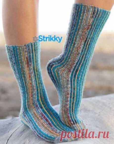 Женские носки от Drops Design вязаные спицами Носки вяжутся спицами поперёк, и этим данная модель от Drops Design отличается ото всех других моделей носков, выполненных традиционным способом. Основной узор – платочная вязка (пл/в). Цветовая гамма изделия переменная, создаётся чередованием двух меланжевых нитей, среди которых непременно присутствуют сине-бирюзовые оттенки.